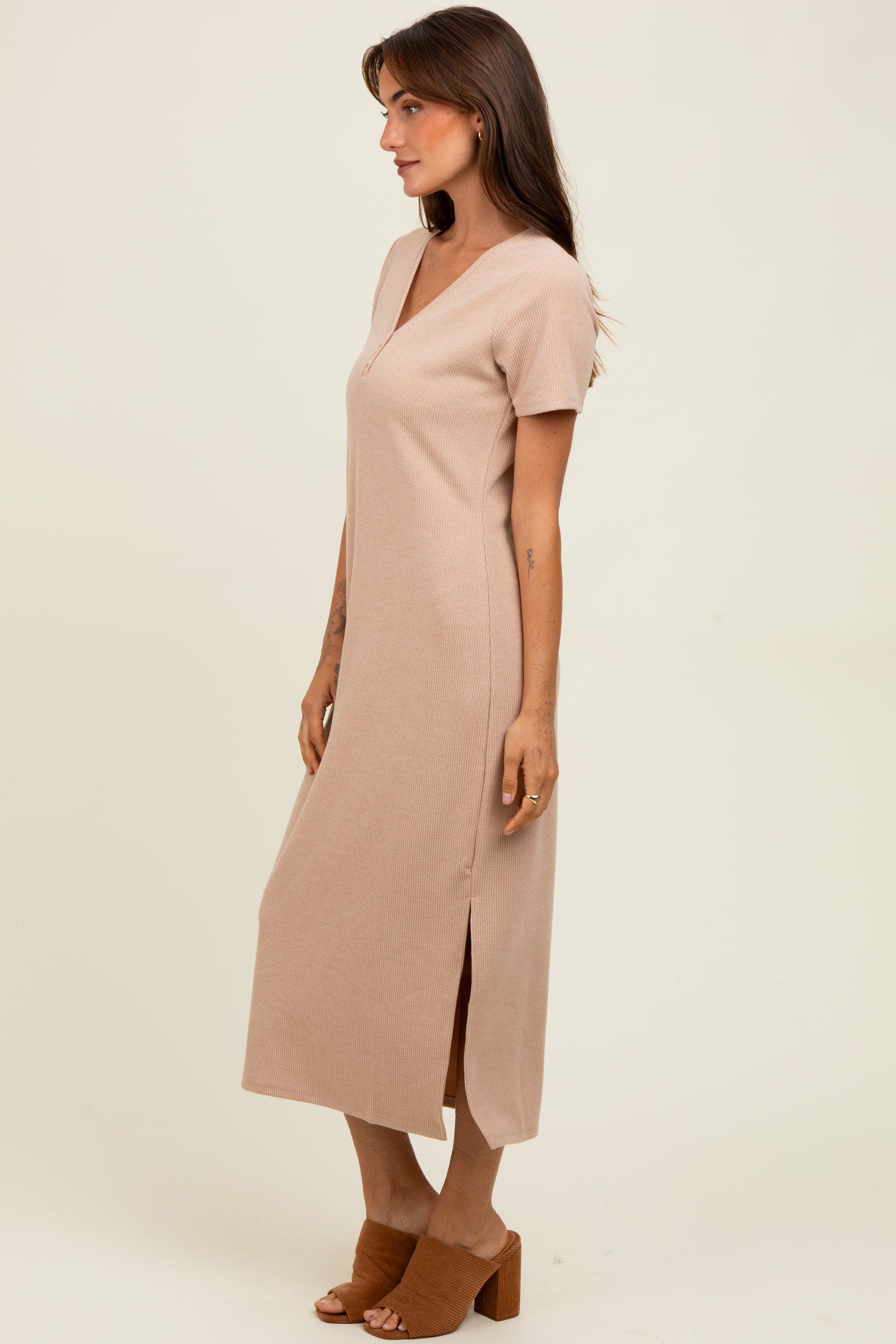 woman wearing a beige short sleeve maxi dress with a v-neck and side slit, standing against a neutral background