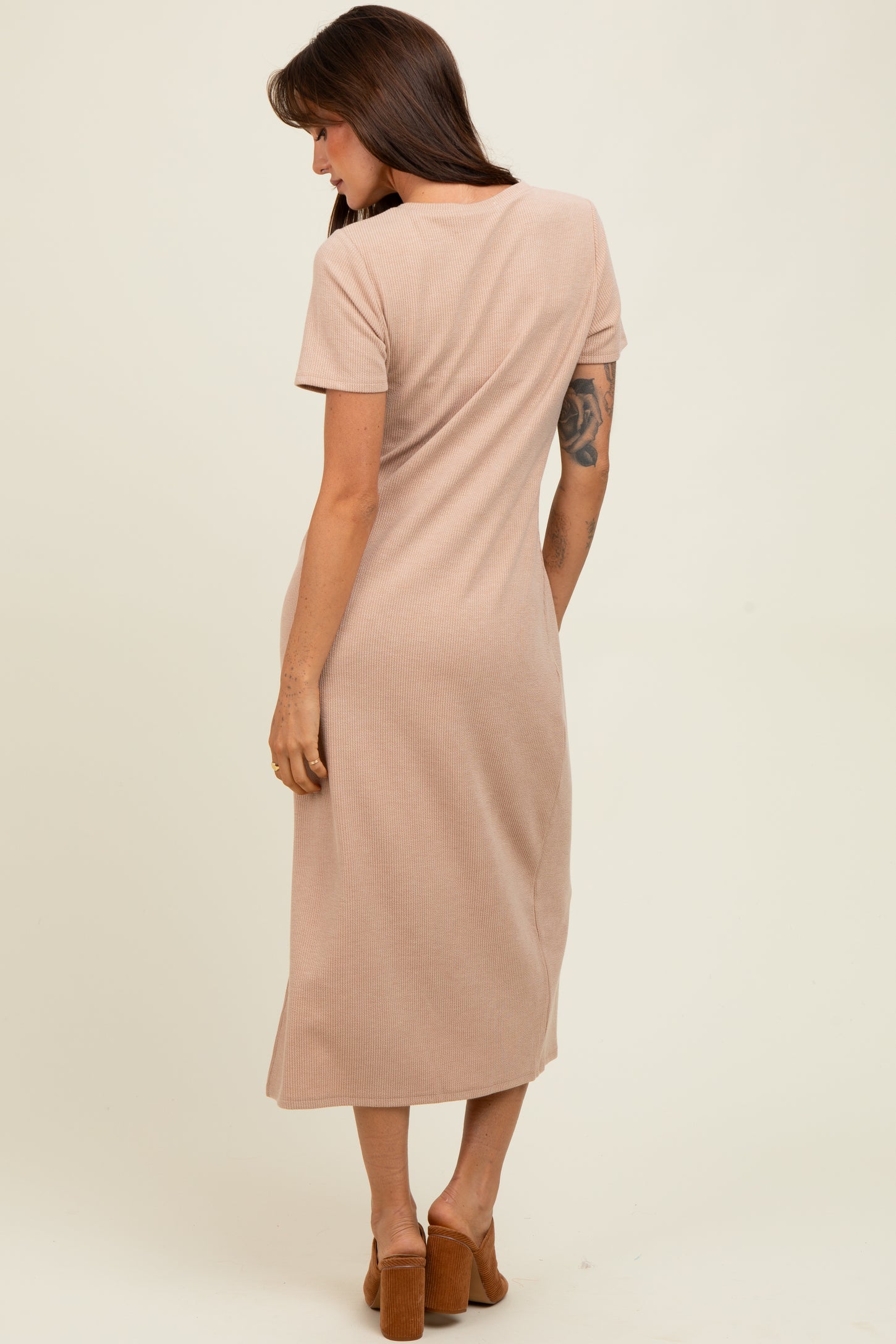 woman wearing a taupe ribbed midi dress with short sleeves, standing with back to camera and wearing brown block-heel sandals