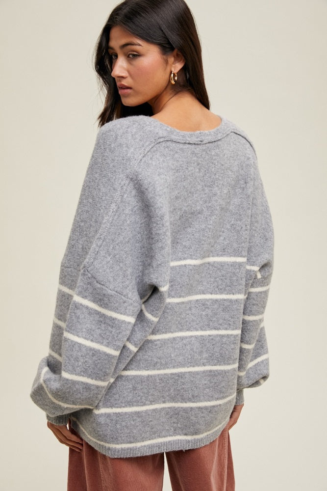 woman wearing a gray striped oversized sweater with drop shoulders and a relaxed fit, seen from the back