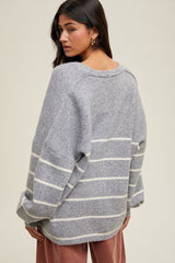 woman wearing a gray striped oversized sweater with drop shoulders and a relaxed fit, seen from the back