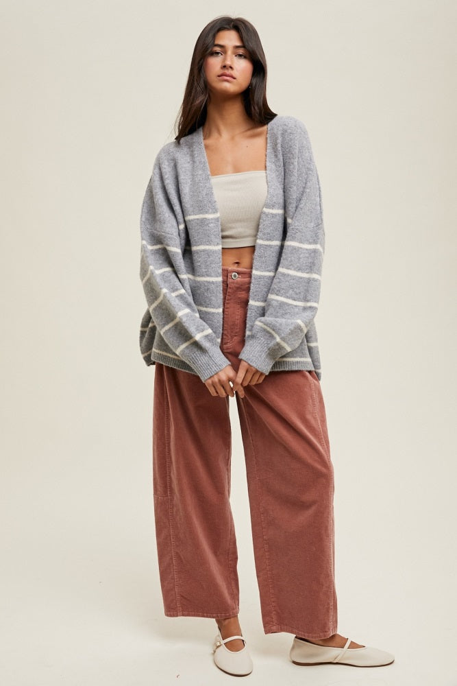 woman wearing a gray striped oversized cardigan, crop top, and rust-colored wide-leg pants