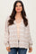 woman wearing a light beige cardigan with white stripes over a beige top and blue jeans