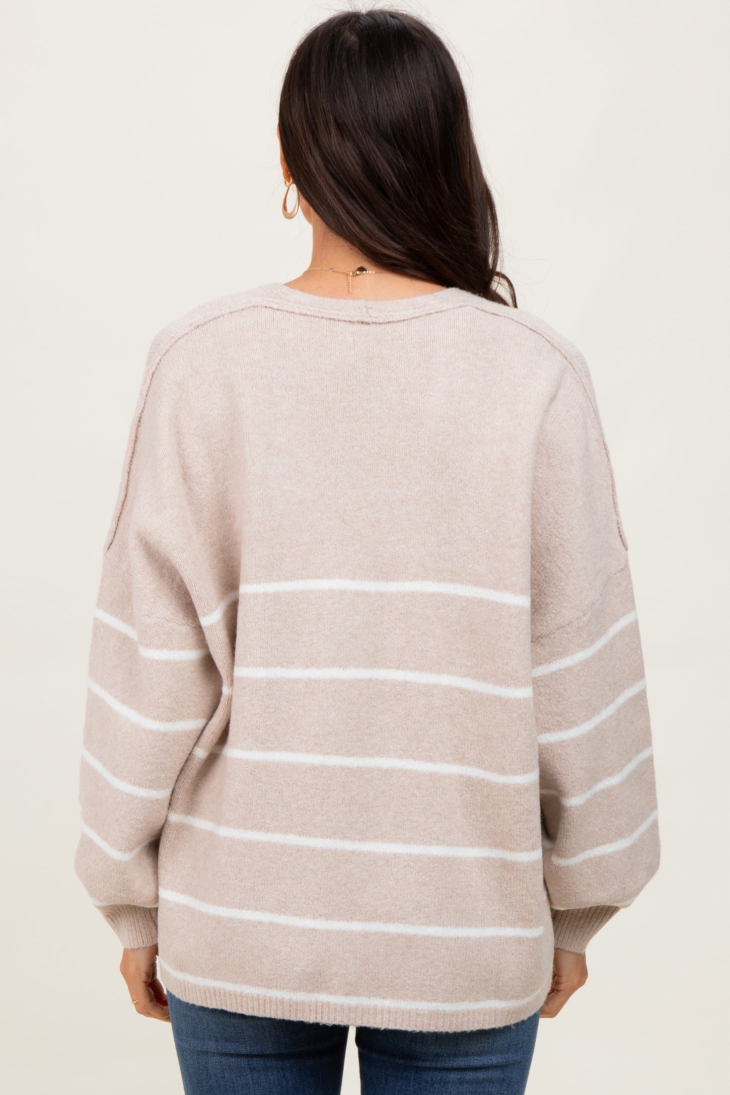 woman wearing a beige and white striped oversized sweater with balloon sleeves, viewed from the back