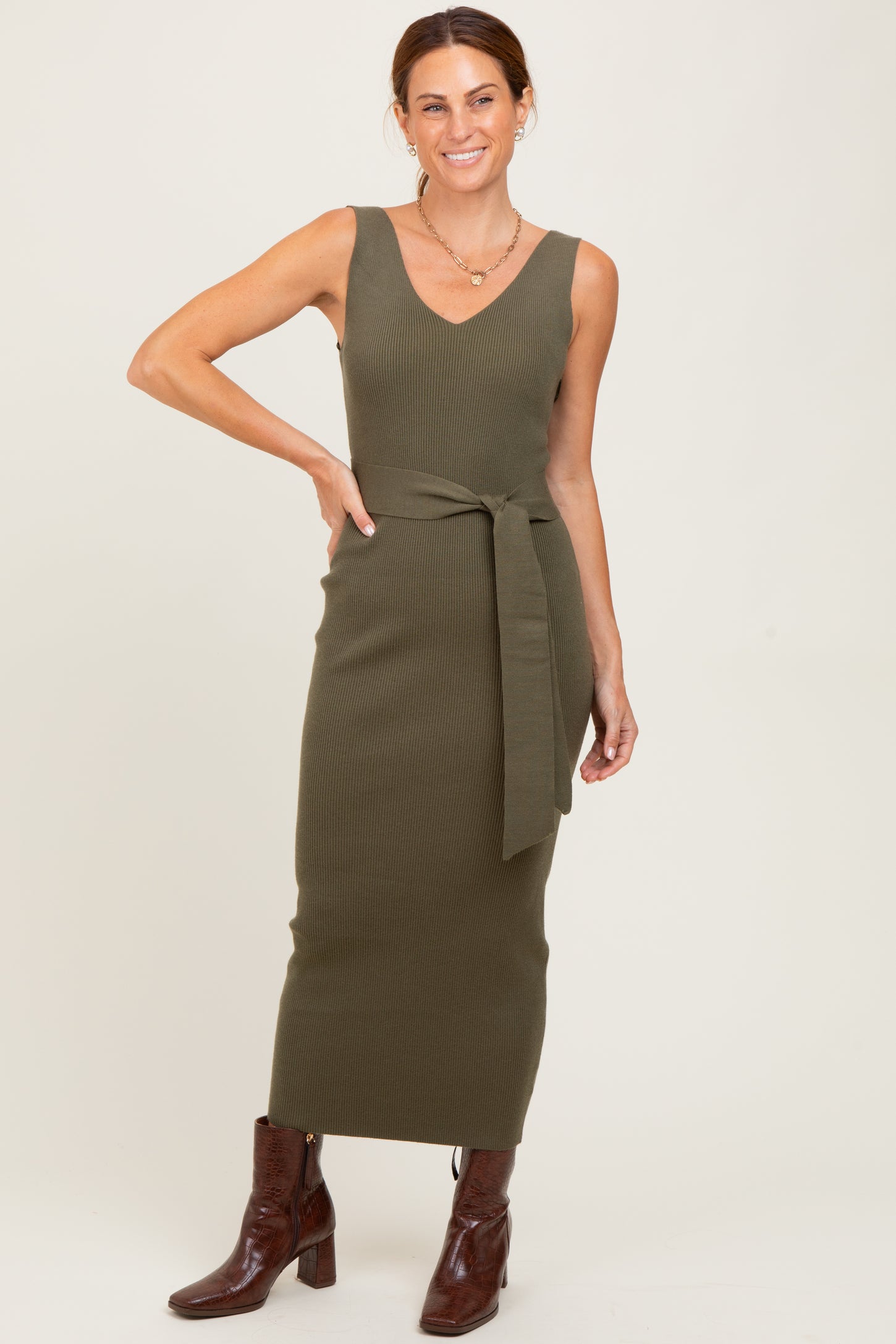woman wearing an olive green ribbed knit maxi dress with a tie belt and brown knee-high boots