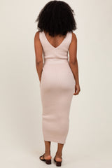 woman wearing a fitted light pink ribbed midi dress with a v-back and side slit
