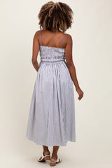 woman wearing a striped maternity maxi dress with a smocked bodice and adjustable straps
