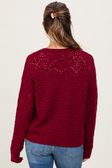 woman wearing a burgundy open knit maternity sweater with long sleeves, viewed from the back