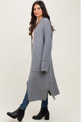 woman wearing a long gray ribbed cardigan over a beige top and blue jeans, paired with black ankle boots
