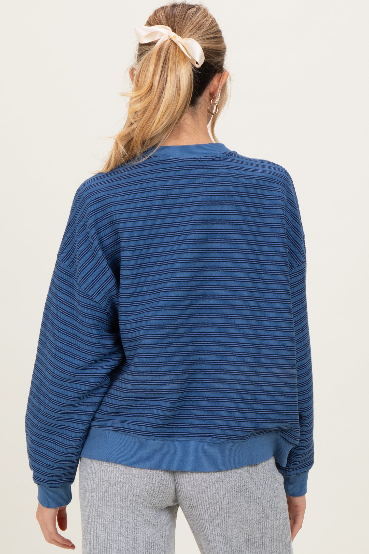 woman wearing a blue striped maternity sweatshirt with a relaxed fit and back detailing