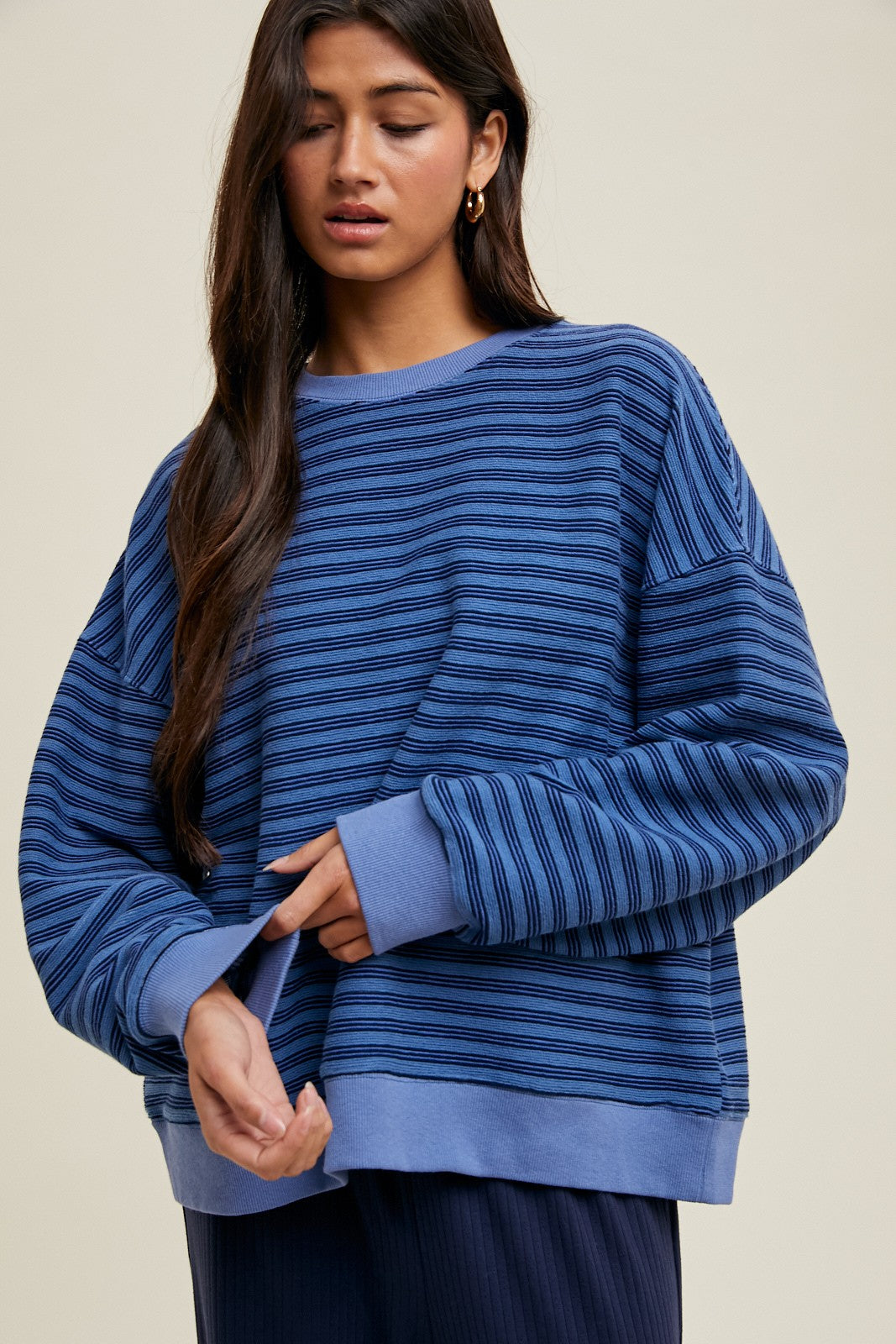 woman wearing a blue striped oversized sweatshirt with long sleeves and a relaxed fit