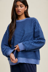 woman wearing a blue striped oversized sweatshirt with long sleeves and a relaxed fit