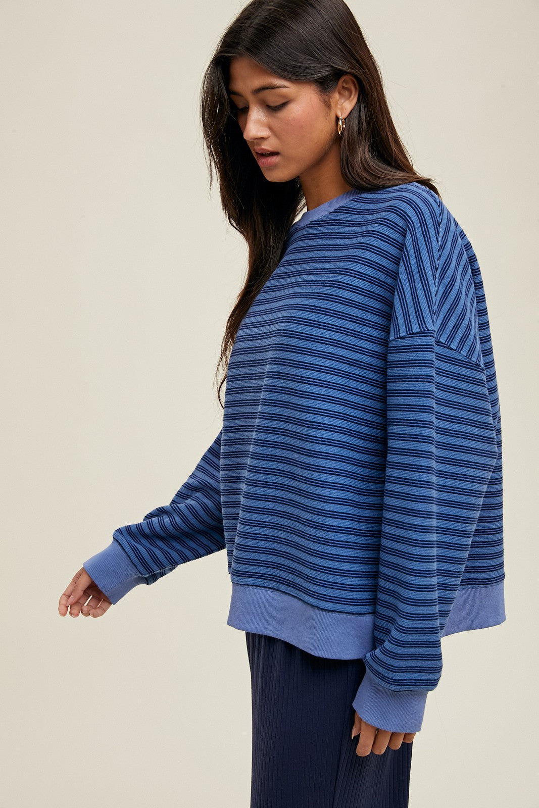 woman wearing a dark blue striped oversized sweatshirt with long sleeves and a relaxed fit