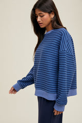 woman wearing a dark blue striped oversized sweatshirt with long sleeves and a relaxed fit