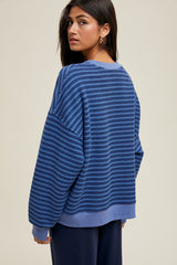 woman wearing a blue striped oversized sweater, showing the back and relaxed fit, paired with dark ribbed pants