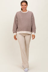 woman wearing a beige and brown striped maternity sweatshirt paired with beige ribbed maternity pants