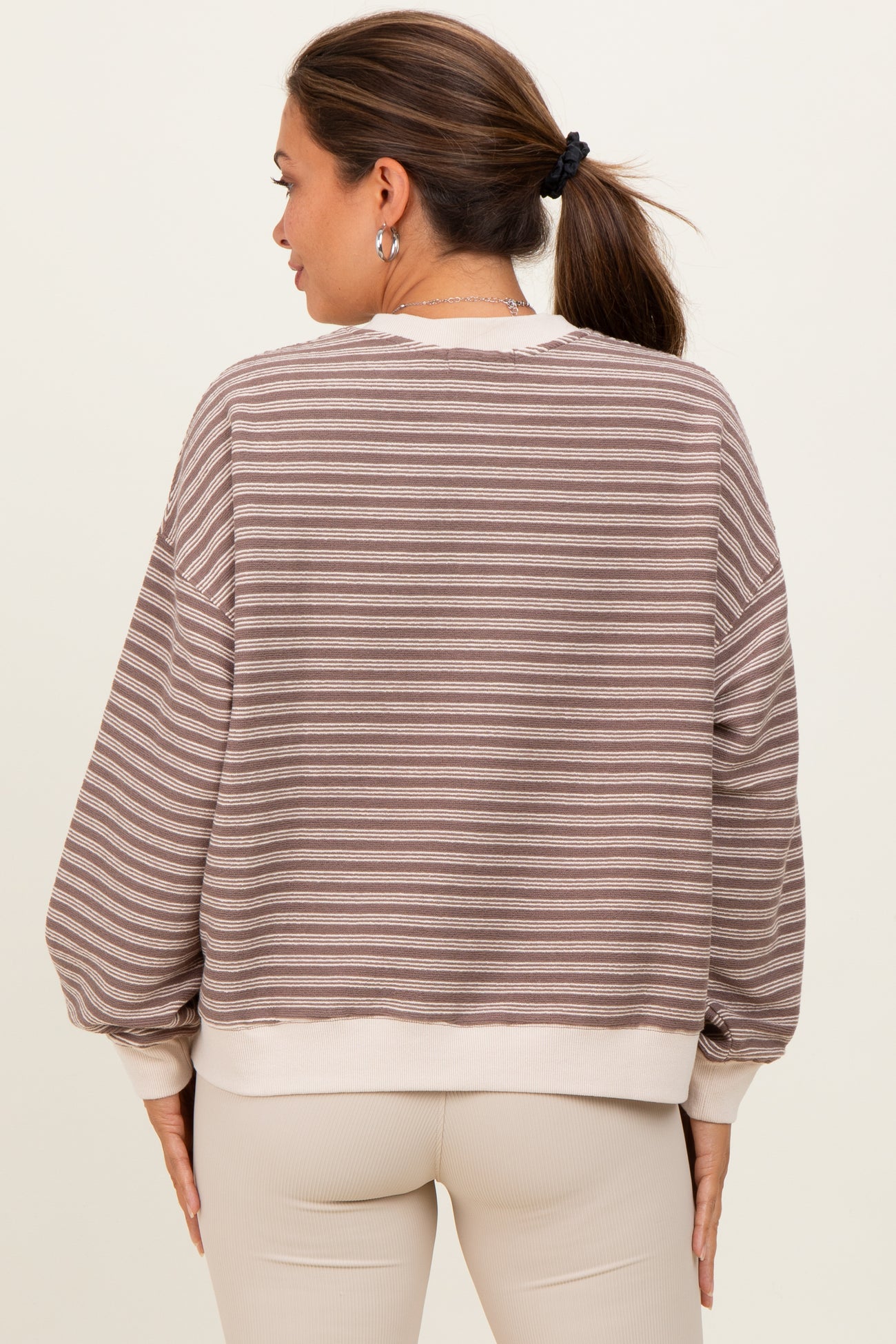 woman wearing a striped beige and brown maternity sweatshirt with a relaxed fit and balloon sleeves