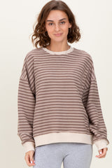 woman wearing a brown and cream striped oversized sweatshirt with a ribbed hem and relaxed fit