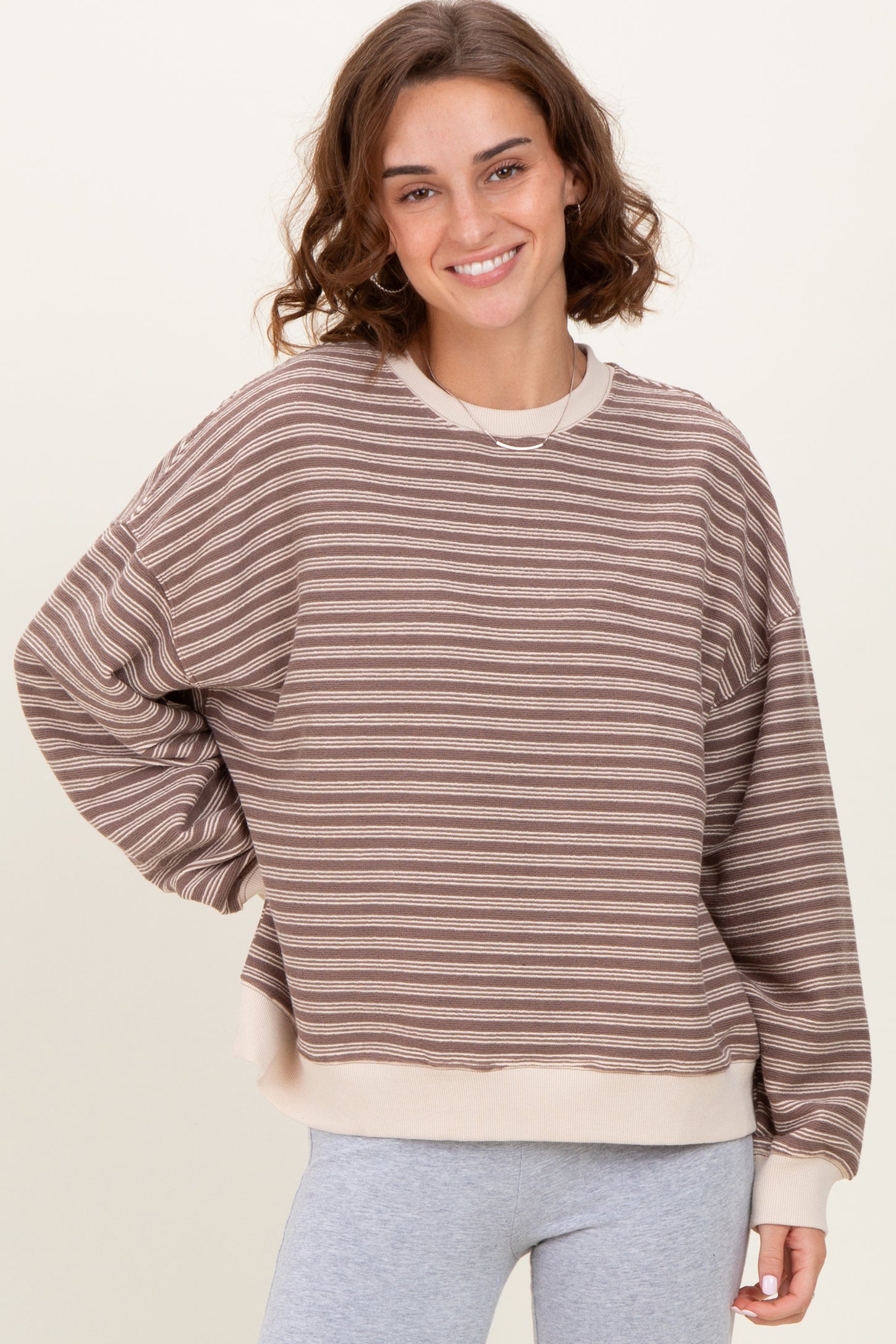 woman wearing a brown and cream striped oversized sweatshirt with long sleeves and a relaxed fit