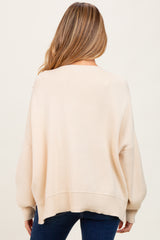woman wearing a beige oversized maternity sweater with a loose fit, showing the back view