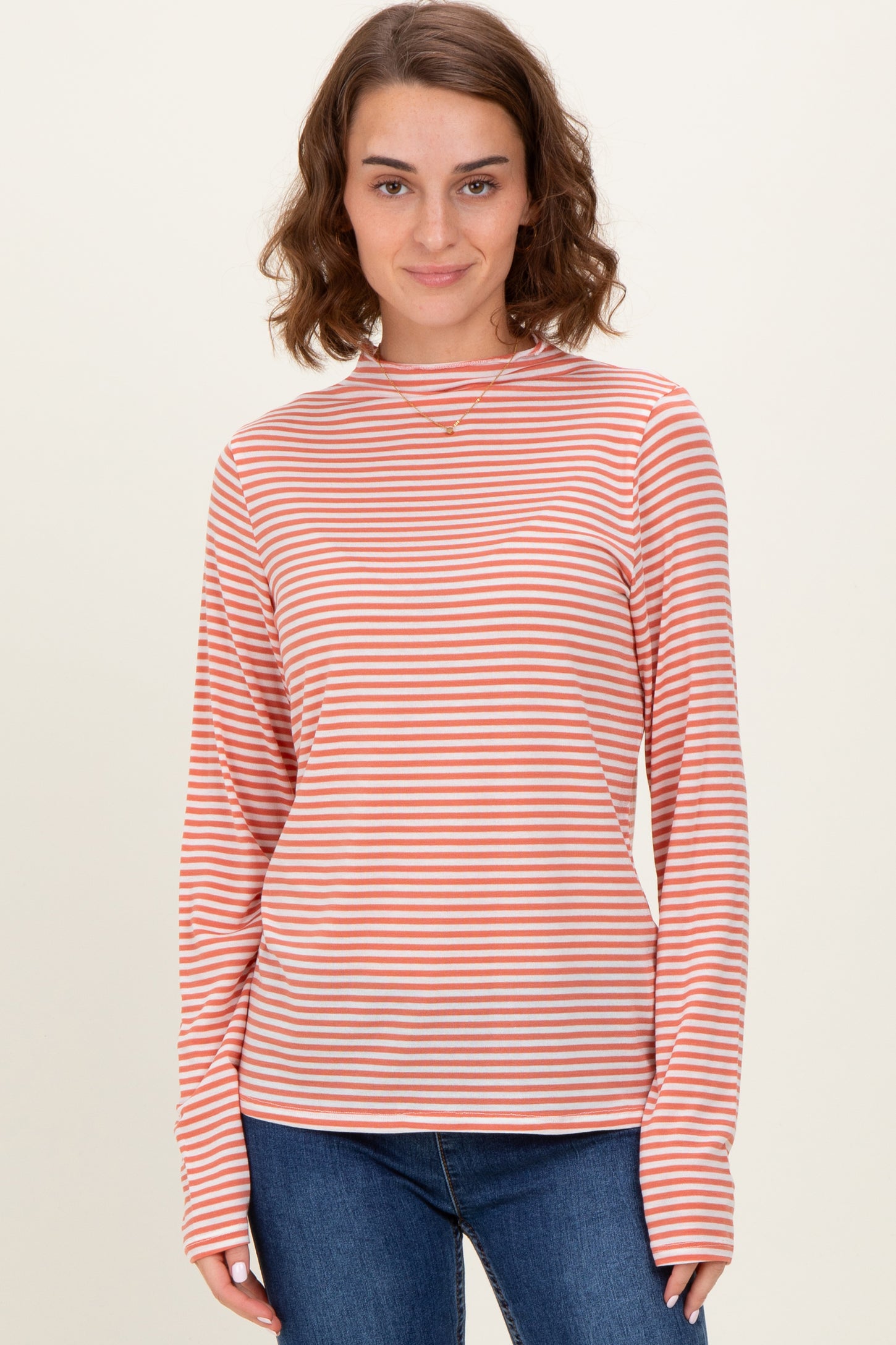 woman wearing a long sleeve orange and white striped top with a relaxed fit and crew neckline