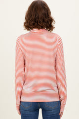woman wearing a striped long sleeve top in light orange and white, facing away from the camera, with blue jeans