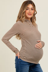 woman wearing a brown and cream striped long sleeve maternity top and holding her baby bump