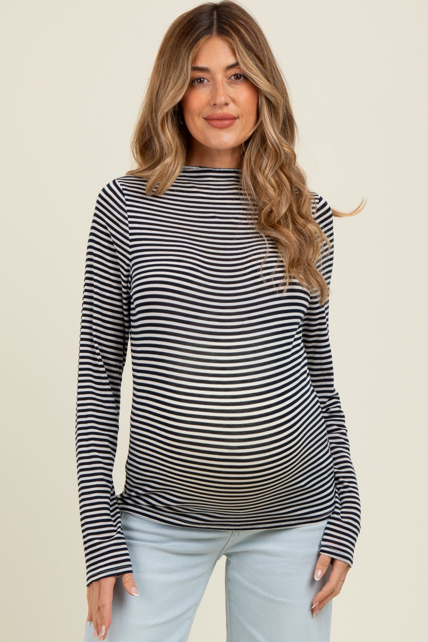 woman wearing a black and white striped maternity top and showing her baby bump