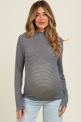 woman wearing a black and white striped maternity top and showing her baby bump