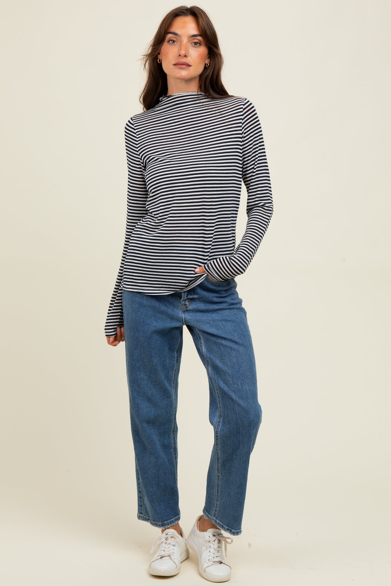 woman wearing a black and white striped long sleeve top, paired with light blue high-waisted jeans and white sneakers