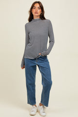 woman wearing a black and white striped long sleeve top, paired with light blue high-waisted jeans and white sneakers