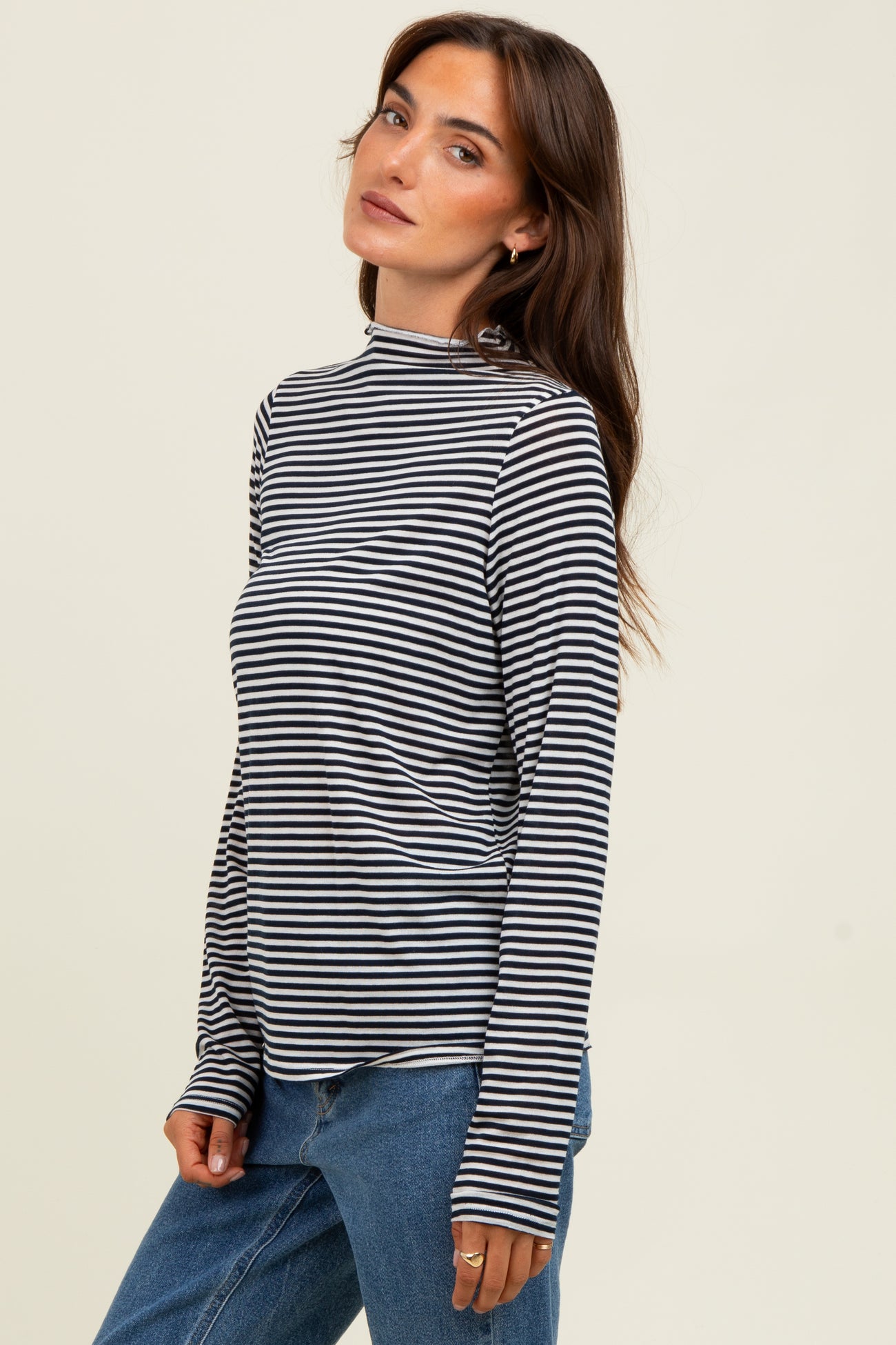 woman wearing a black and white striped long sleeve top with a mock neck and relaxed fit jeans
