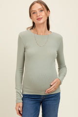 woman wearing a light green long sleeve maternity top and holding her baby bump