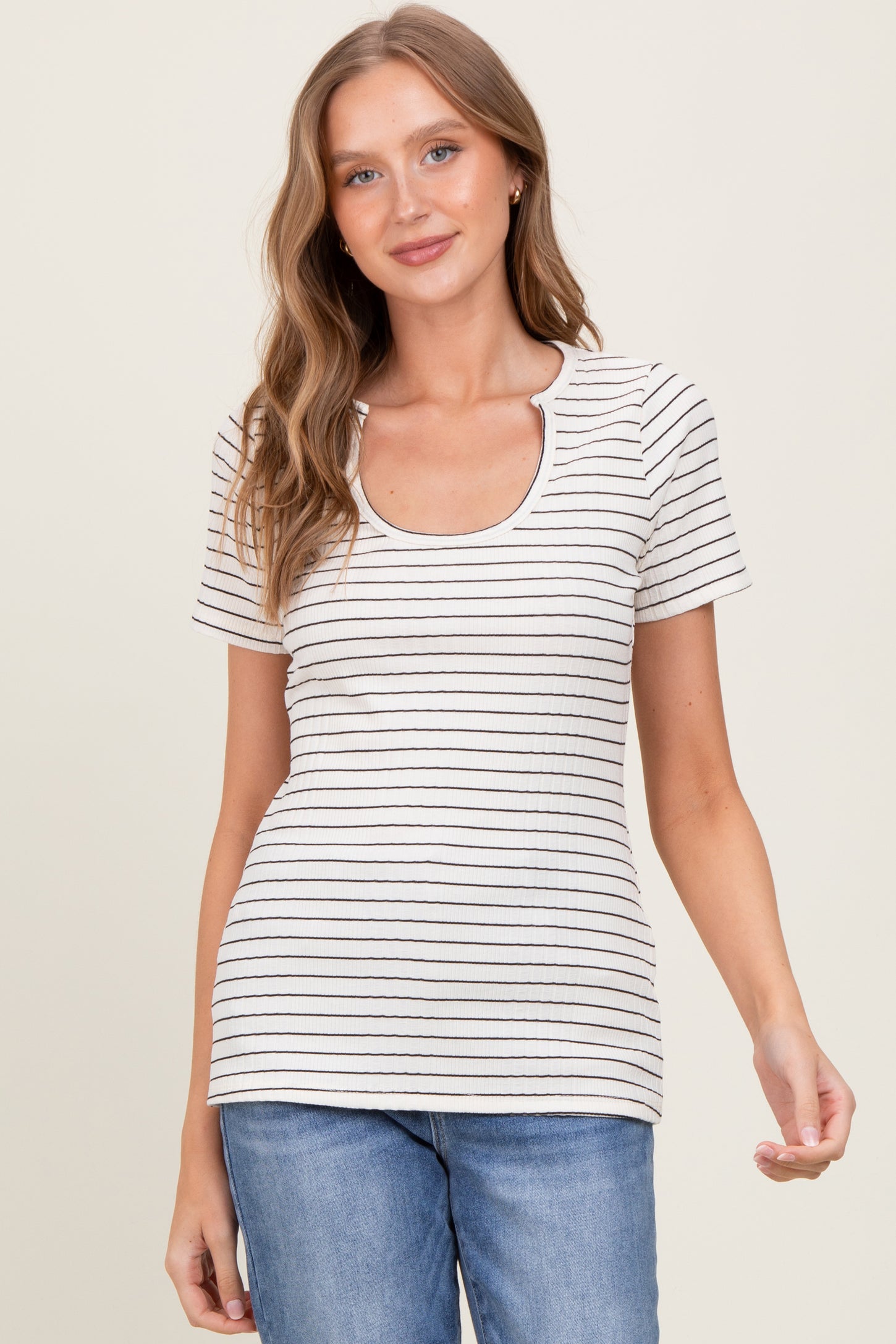 woman wearing a cream striped scoop neck short sleeve top with a fitted silhouette and blue jeans