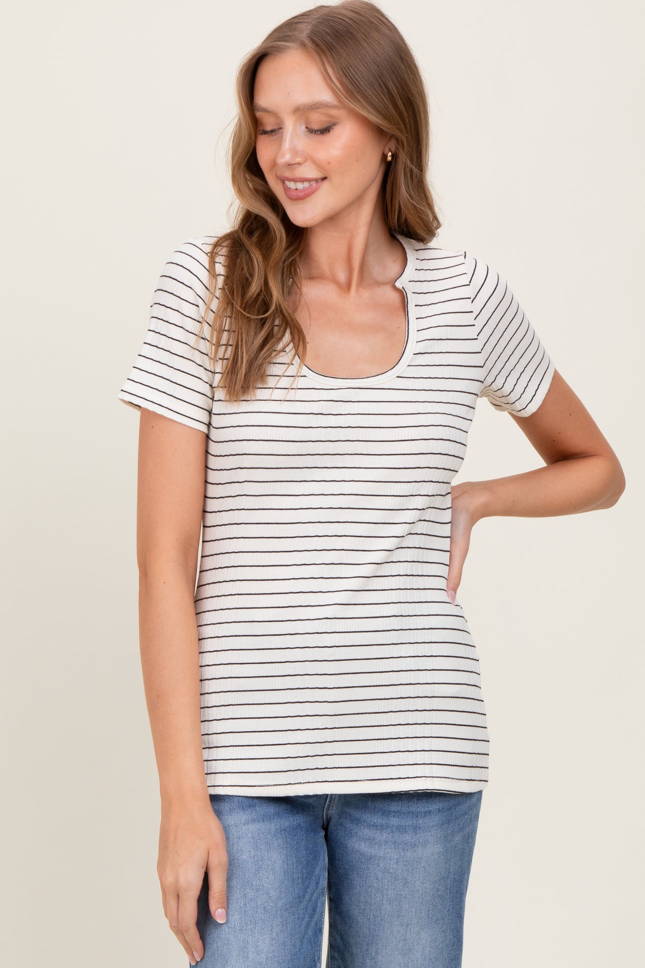woman wearing a cream striped short sleeve top with a scoop neckline and light blue jeans
