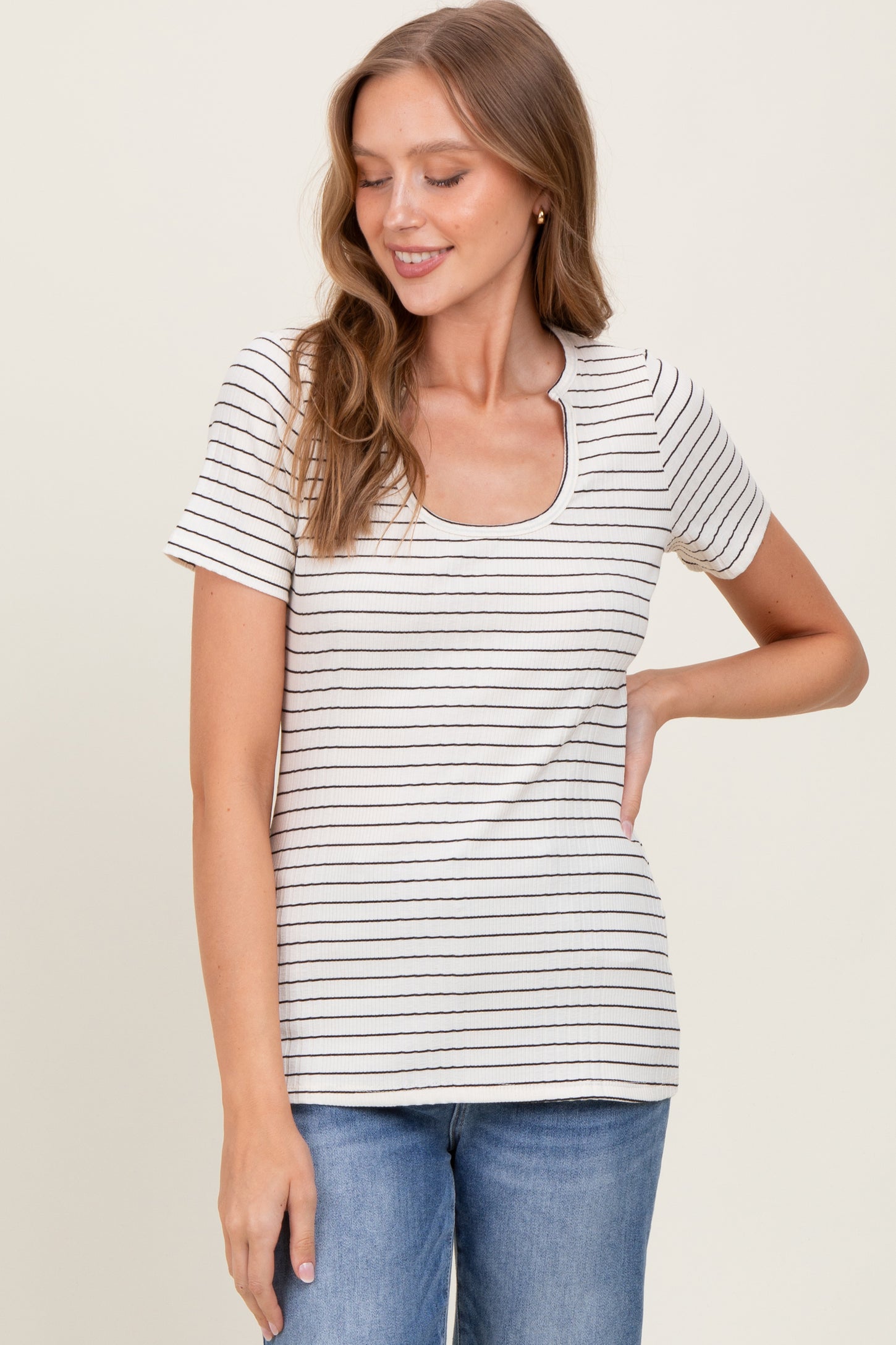 woman wearing a cream striped short sleeve top with a scoop neckline and light blue jeans