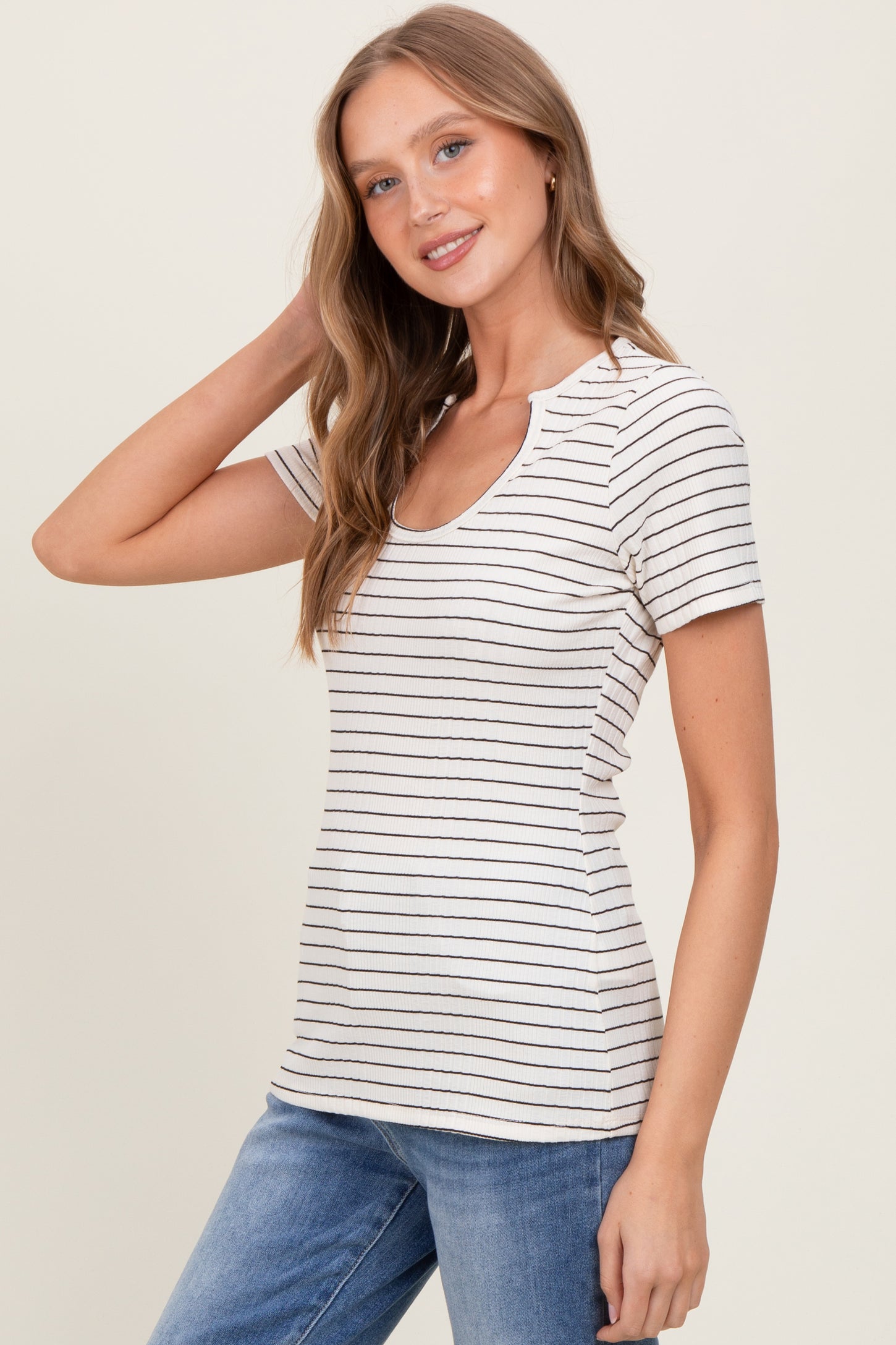woman wearing a cream striped short sleeve top with a scoop neckline and fitted style