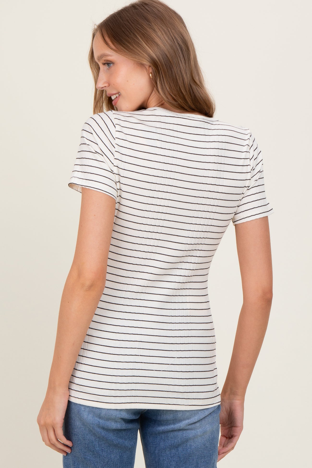 woman wearing a fitted white and navy striped t-shirt with short sleeves and side gathering