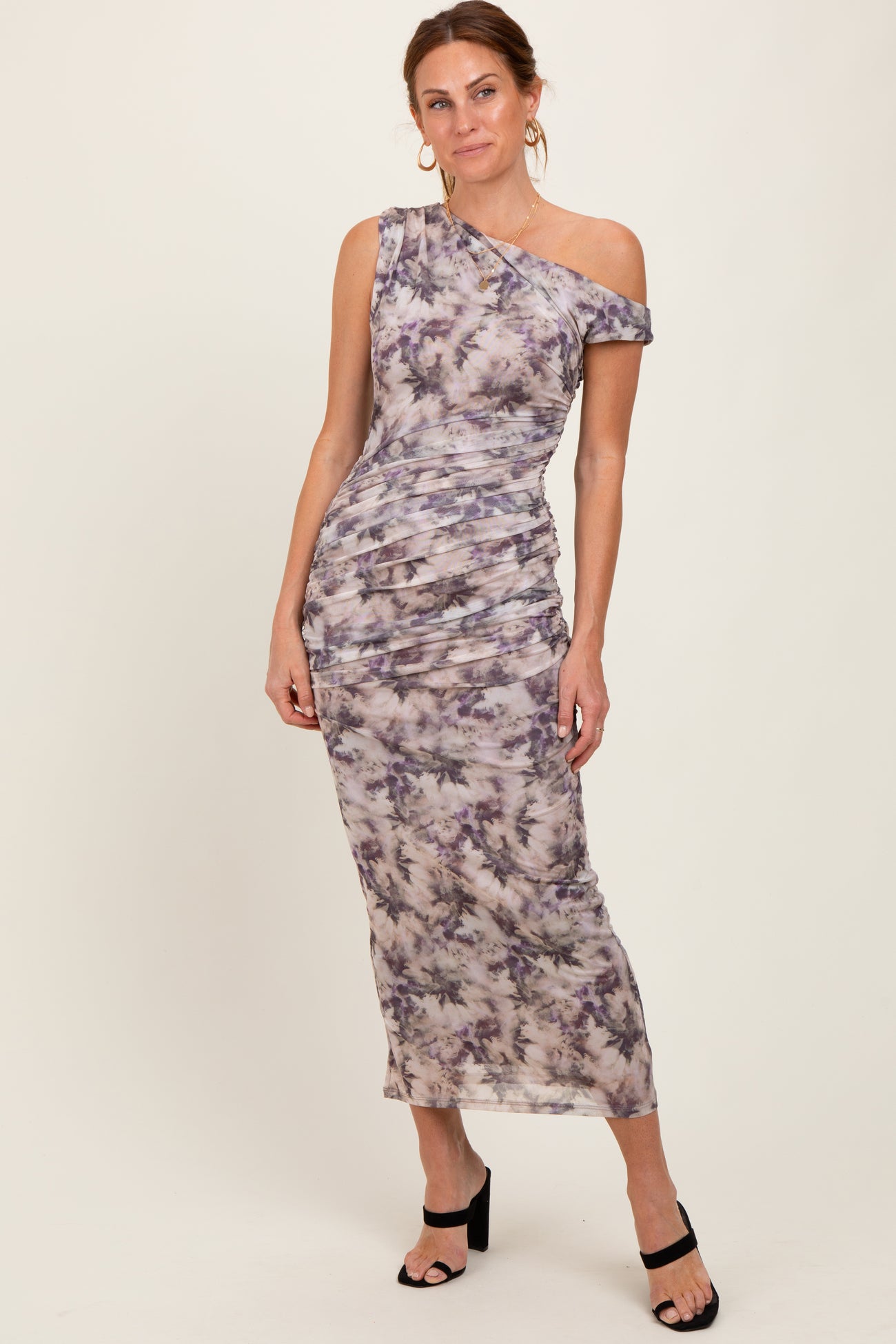 woman wearing a one-shoulder floral maxi dress with ruching and a fitted silhouette