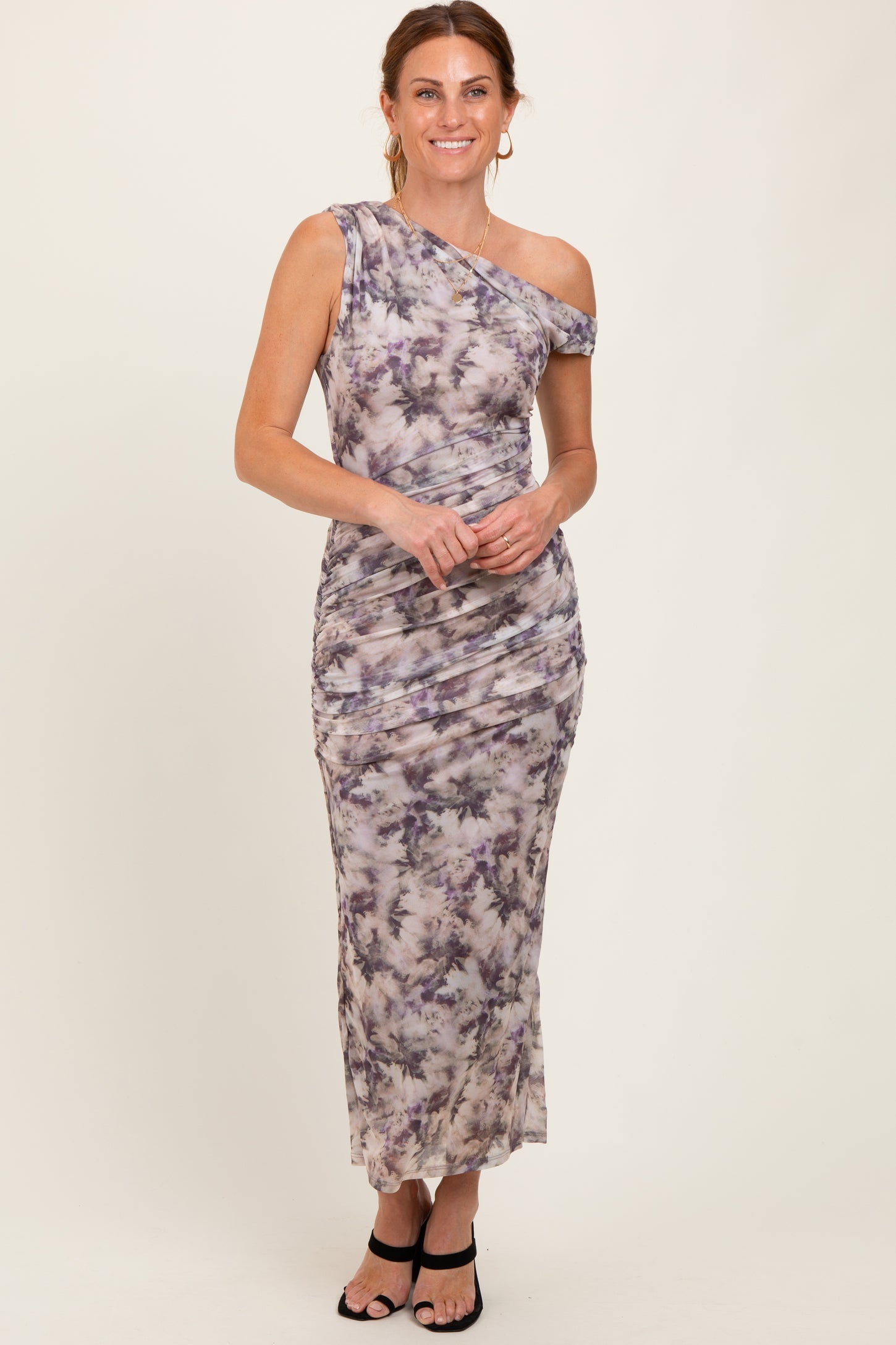 woman wearing a one-shoulder tie-dye maxi dress with ruching details and a fitted silhouette