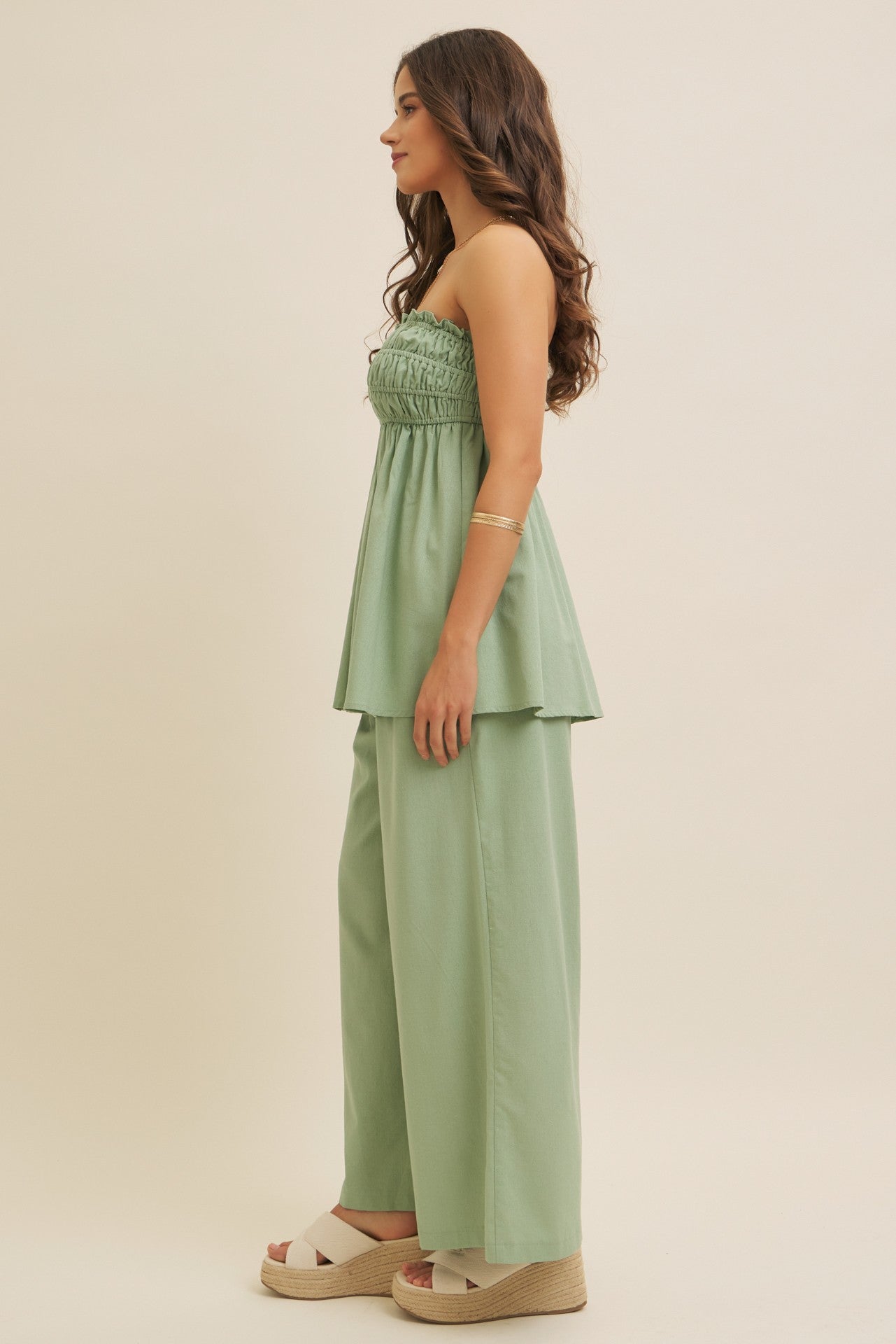 woman wearing a light green strapless smocked top with matching wide-leg pants and platform espadrilles