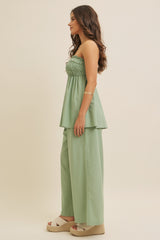 woman wearing a light green strapless smocked top with matching wide-leg pants and platform espadrilles