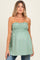 woman wearing a green strapless maternity top with smocked detailing and a loose fit, showcasing her baby bump