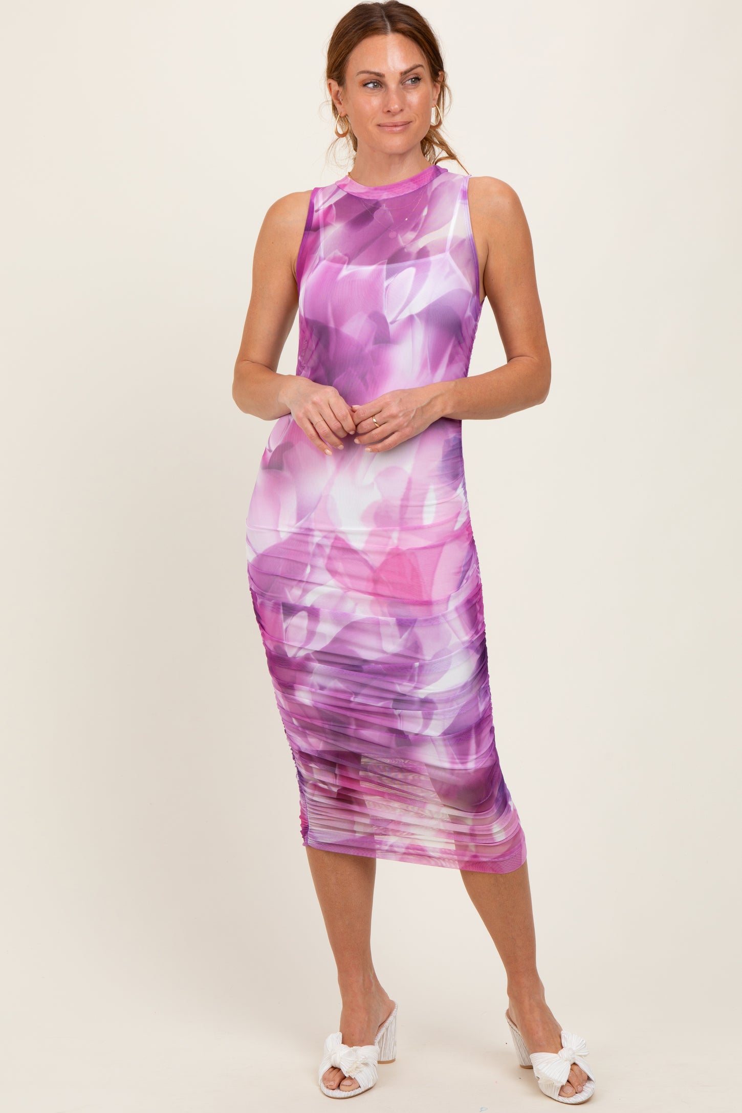 woman wearing a purple floral print midi dress with ruching detail and a sleeveless design