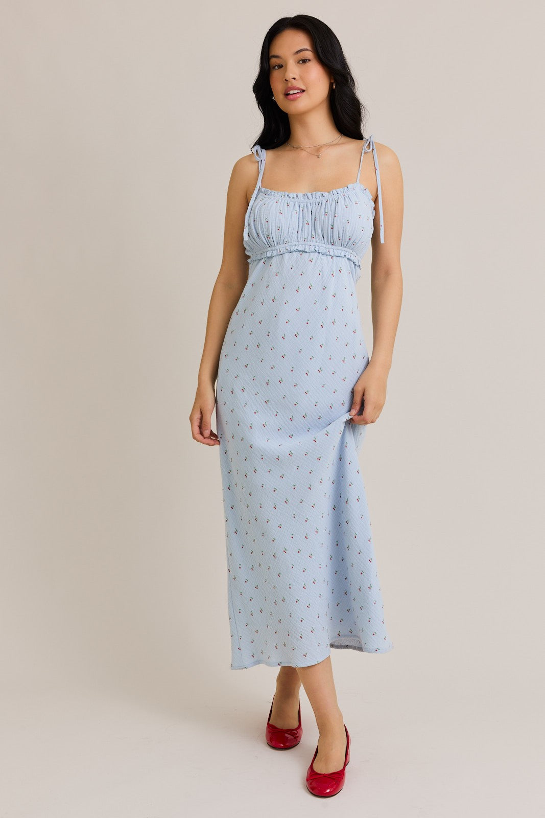 woman wearing a light blue floral maxi dress with adjustable straps and gathered bodice