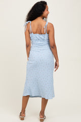 woman wearing a light blue maternity dress with adjustable straps and floral print, showing her back and a baby bump