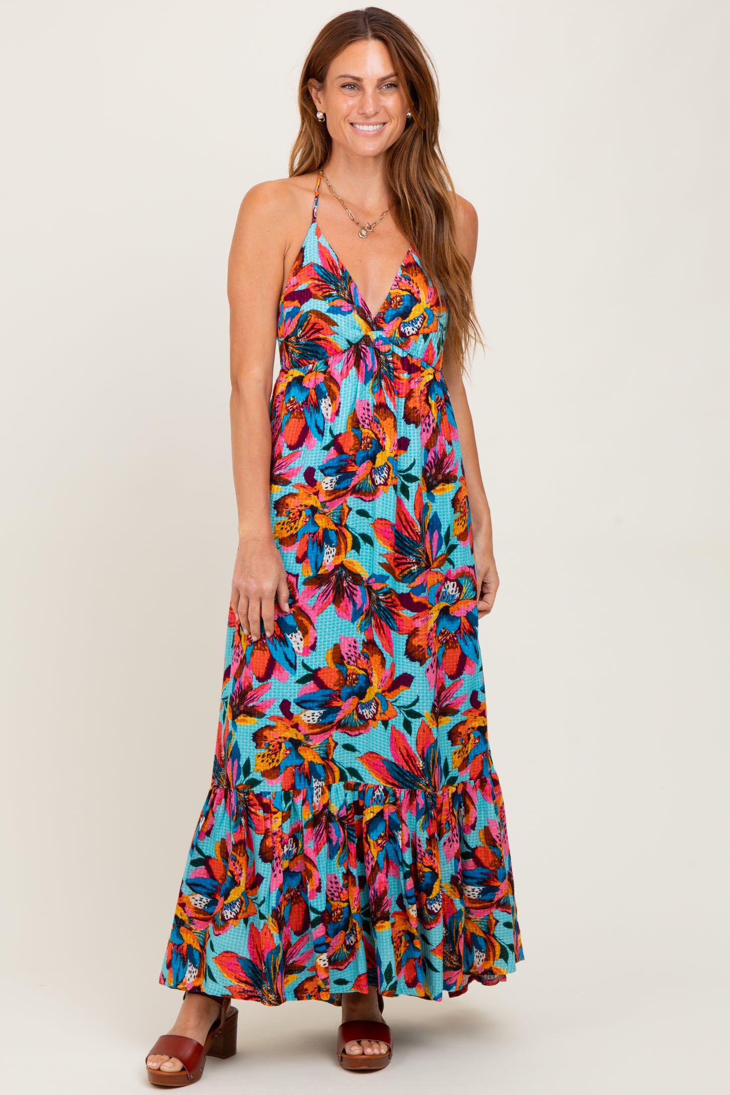 woman wearing a colorful floral maxi dress with a tiered skirt and spaghetti straps