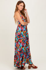 woman wearing a colorful floral maxi dress with a ruffled hem and a low back