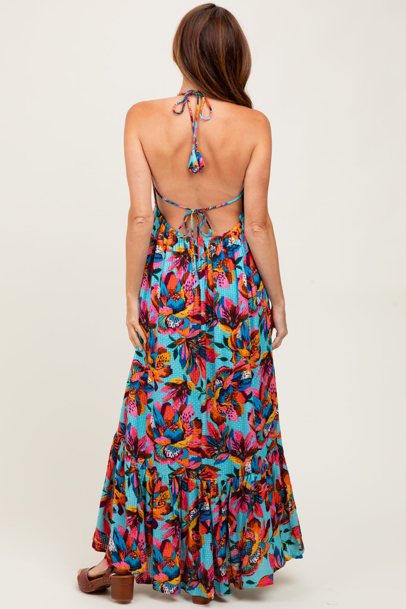 woman wearing a backless maxi dress with a colorful floral pattern and ruffled hem