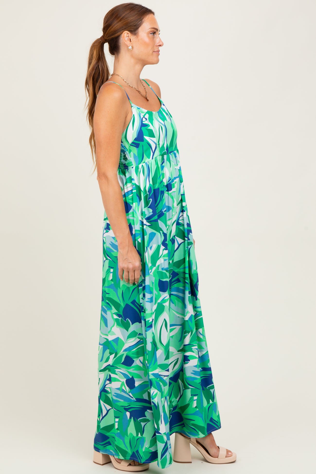 woman wearing a bright green floral maxi dress with a fitted bodice and flowy skirt, styled with a side view