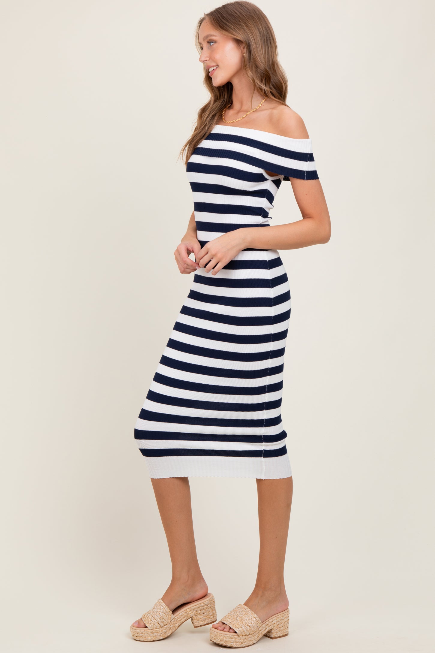 woman wearing a navy and white striped off-the-shoulder midi dress with a fitted silhouette and side slits